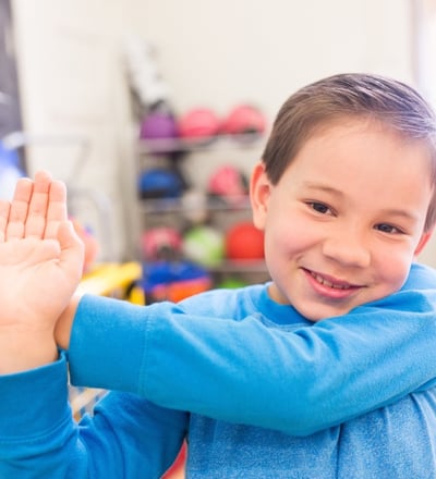 Elementary boy does a shoulder stretch.