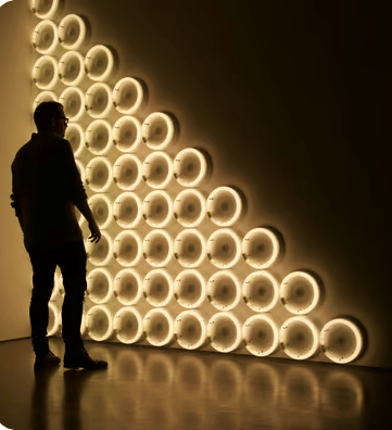 a man standing in front of a wall with a large light