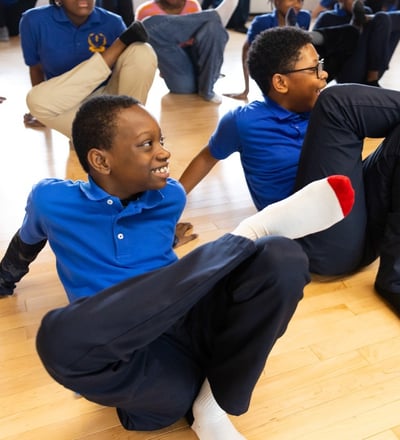 Students do a leg stretch together.