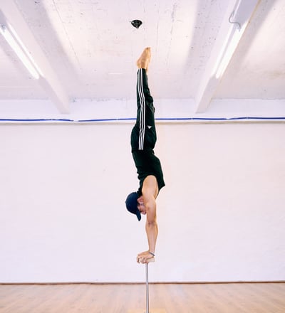 Man voert een rechte handstand uit op canes bij De Polecats Fabriek in Gent