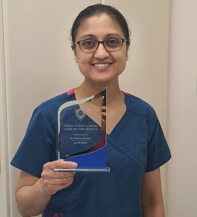 a lady dentist in scrubs and holding a trophy