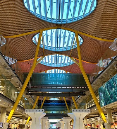 Inside Madrid-Barajas airport Terminal 4, with orange supports holding a wood and glass canopy