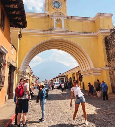 Eva in front of the iconic yellow arch of Antigua, Guatemala.