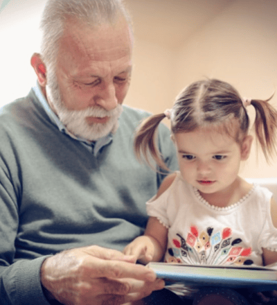 an elderly gentleman reading to a young girl