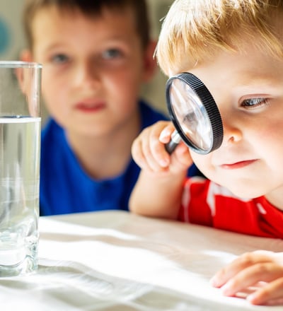 a boy looking through a magnifying glass at Reno preschool