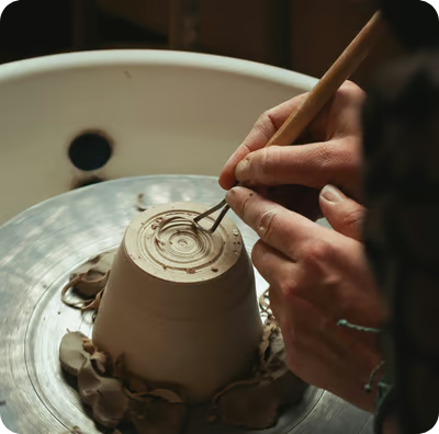 a person is making a clay potted with a wooden spoon