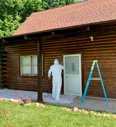 Professional Painter Spraying a Cabin Door for a Smooth, High-Quality Finish