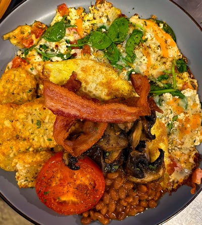 a plate of food with eggs, hashbrowns, bacon, beans, mushrooms