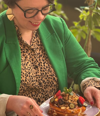 a woman in a green jacket and glasses is holding a plate with a plate of