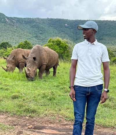 Moses Ole Njapit stands beside two white rhinos, Kofi Annan and Queen Elizabeth