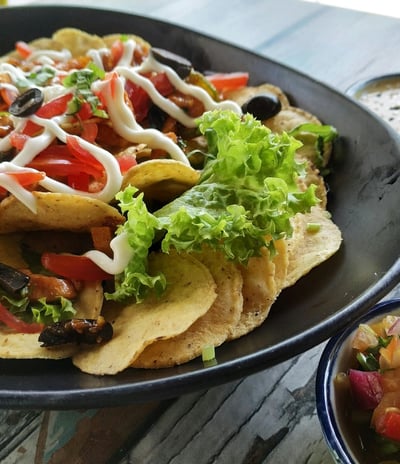 A taco on a black plate with visible fillings and sauces, neatly arranged with some spilling out.