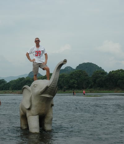 Nick Billington on an elephant  by the river in Guilin, China