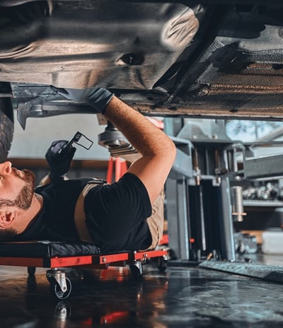 A man working under a car in a garage.