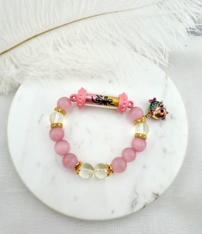 Bracelet Features pink and clear rounded beads alternating in color. It has a central element with 