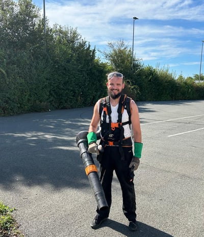 a man in a vest and a backpacker in a parking lot