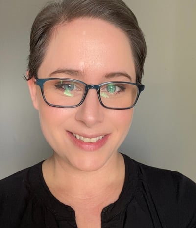 Photo of owner E. O'Hara of Main Street E-Market with black shirt and glasses and pixie cut hair