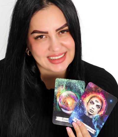 Gabriela Luna, terapeuta espiritual hispana, sonriendo mientras sostiene un tarot Rider-Waite y un c