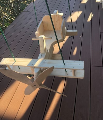 a wooden airplane toy with a wooden swing