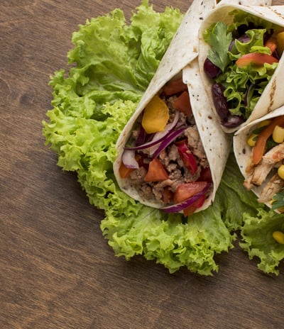 A fully filled taco with seasoned ingredients, including lettuce, tomatoes, and shredded cheese.