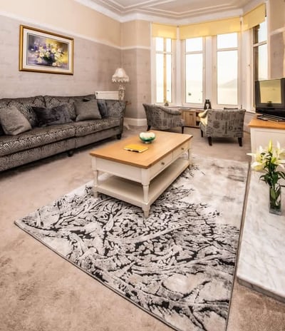 The spacious living room at Gourock Seaview Holiday Let with a couch, armchairs and a fireplace