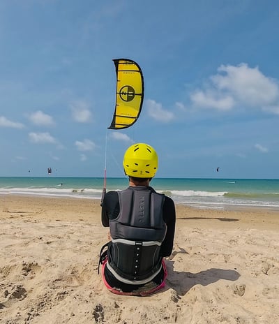 adolescente controlando o kitesurf de frente para a o mar.
