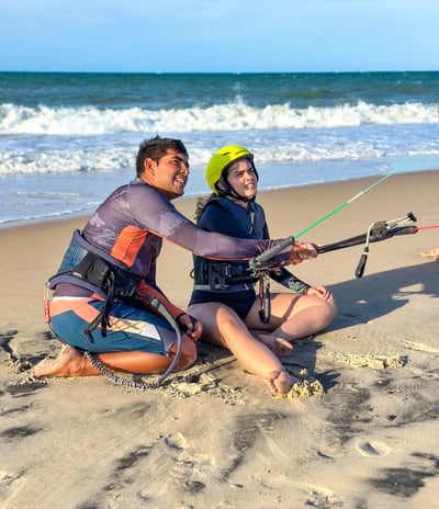 professor de kitesurf dando aula para uma mulher jovem em frente a praia.
