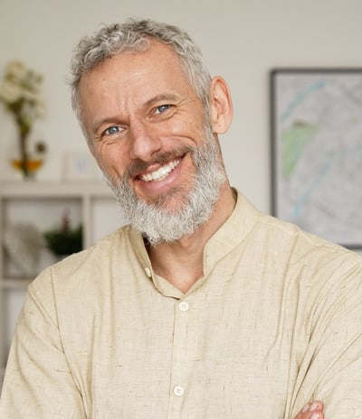 A cheerful older man with a beard smiling confidently, representing positivity and health.