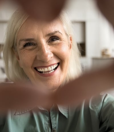 A cheerful older woman smiling, heart gesture, symbolising positivity, ageing gracefully