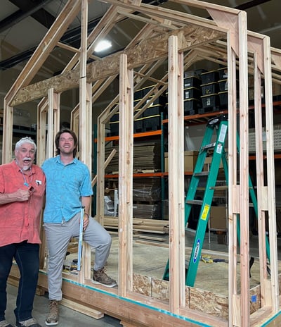two men standing in front of a house construction showing the iwood wooden frame