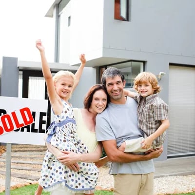 a family standing in front of a sold sign