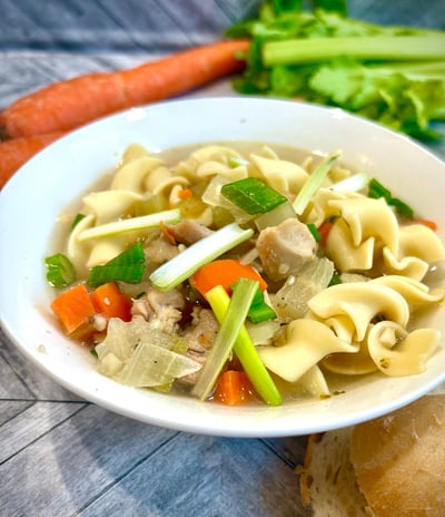 Chicken noodle soup in a white bowl.
