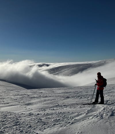 picture of one person viewing snowy fell landscape wiht clouds in valley and clear sky