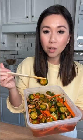 a woman holding a container with vegetables and chopsticks