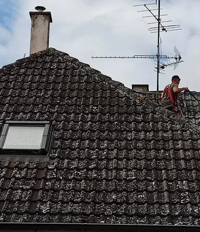 Couvreur réalisant un nettoyage en profondeur d’une toiture envahie par les mousses à Montbéliard, pour restaurer l’étanchéit