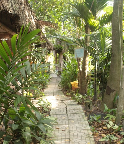 Traditional thatched-roof cottages surrounded by lush gardens at Saigon Garden Homestay.