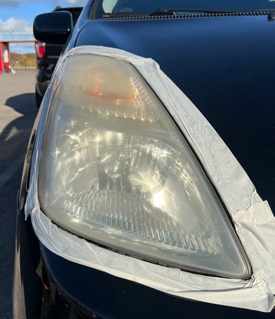 automobilis su balta juostele užklijuotas aplink žibintą, kurį ruošiasi poliruoti