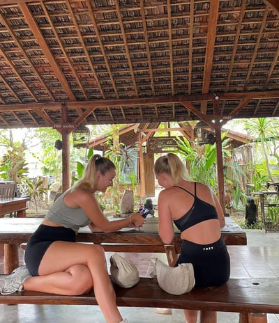 two women sitting on a bench in a wooden table