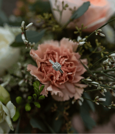 a diamond ring with a diamond ring on top of a bouquet of flowers