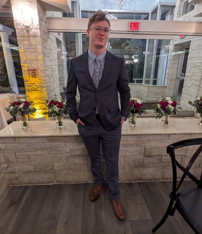 a man dressed in grey suit, brown shoes, and blue dress shirt & tie