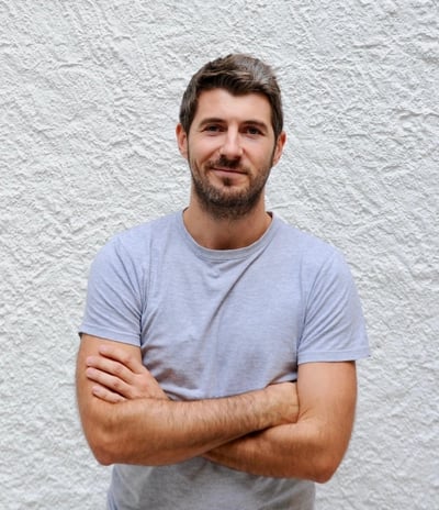 un homme avec une barbe, debout devant un mur blanc