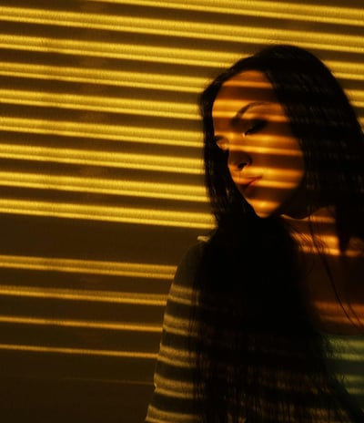 A woman standing near automated window blinds