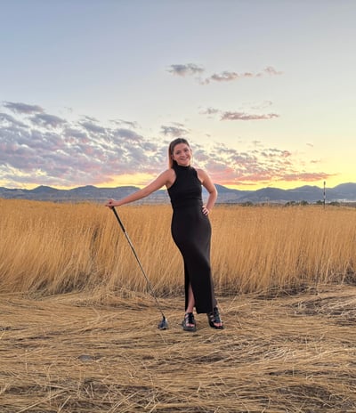 a woman in a black dress standing in a field