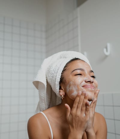 a woman in a towel doing her skin care on her face