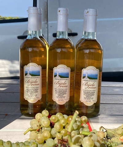 Three bottles of Primošten white wine “Bijelo vino” with grapes in front, produced by OPG Branko Mar