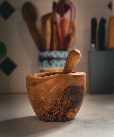 Mortier en bois massif artisanal accompagné de son pilon, posé sur un plan de travail dans une cuisi