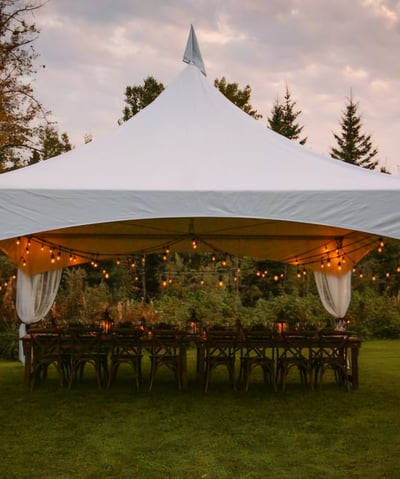 Carpa 20x20 en el patio de una casa, adornada con luces, sillas, mesas