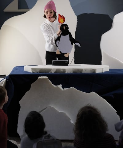 a woman in a pink hat and a penguin on a stage