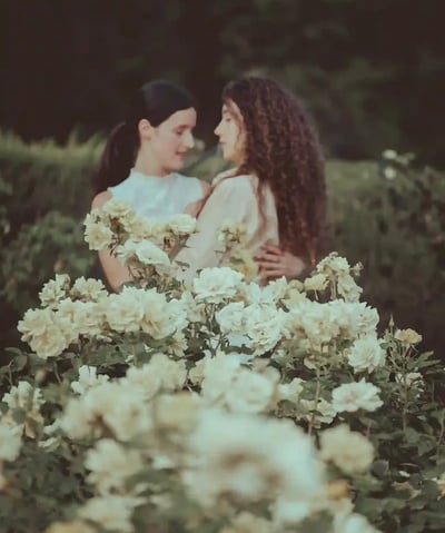"Pareja lesbiana con flores de rosa blanca, celebrando su compromiso en una boda gay."