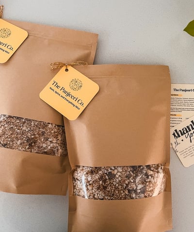 Two sealed, recyclable brown paper bags filled with handcrafted subcontinental granola (Panjeeri).