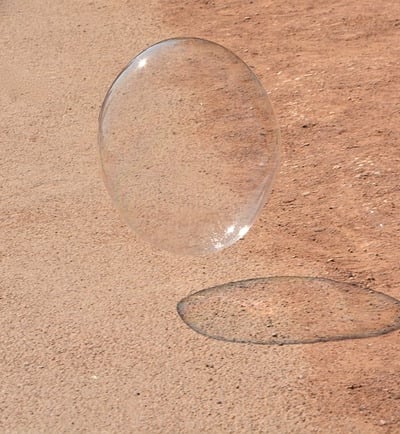 Schwebende Seifenblase auf feinem Wüstensand unter der Sonne